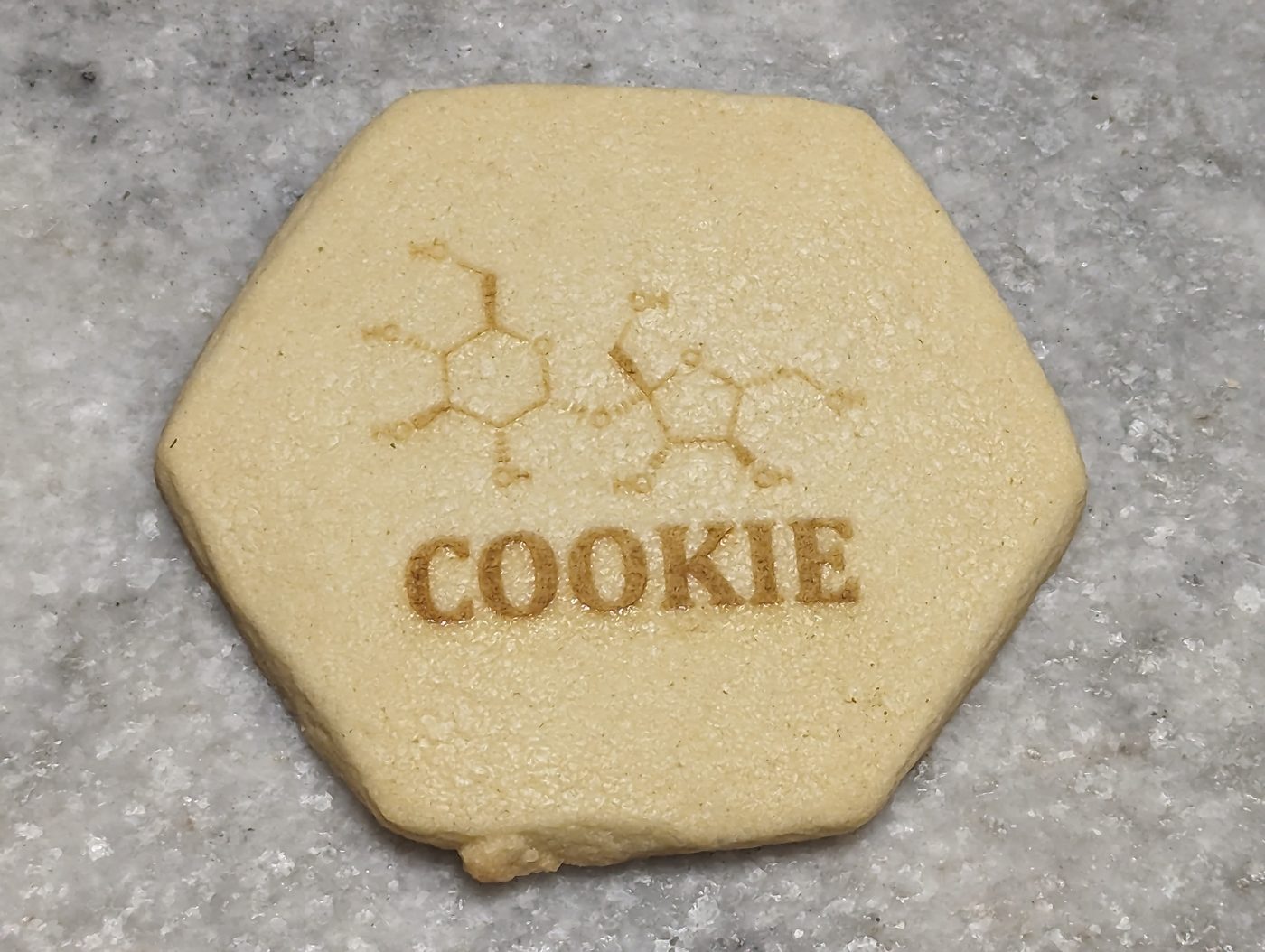 Laser-engraved sugar cookie with a caffeine molecule and the word COOKIE