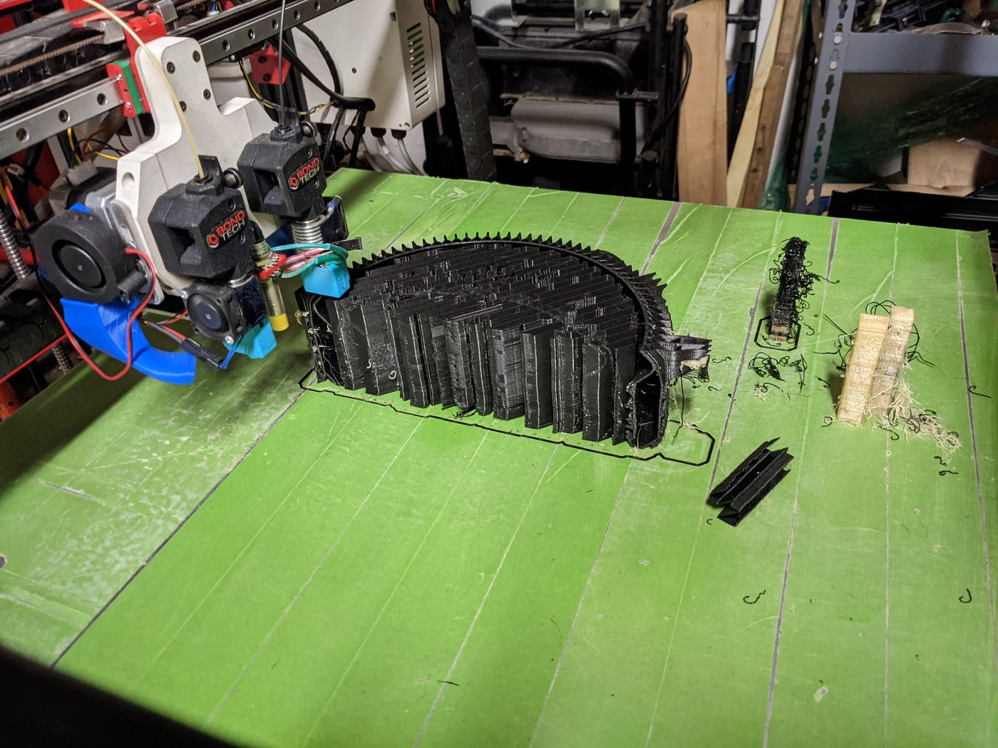 Dual-extruder printer mid-print on a green build plate