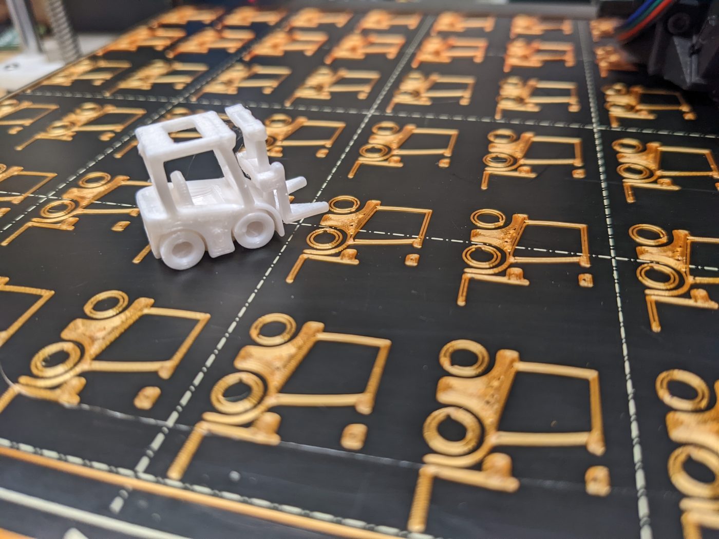 White forklift standing on the printer bed beside first-layer outlines