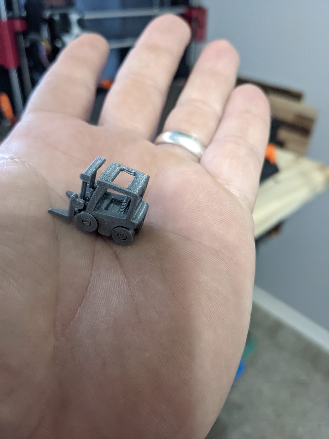 Tiny 3D-printed forklift sitting in an open palm